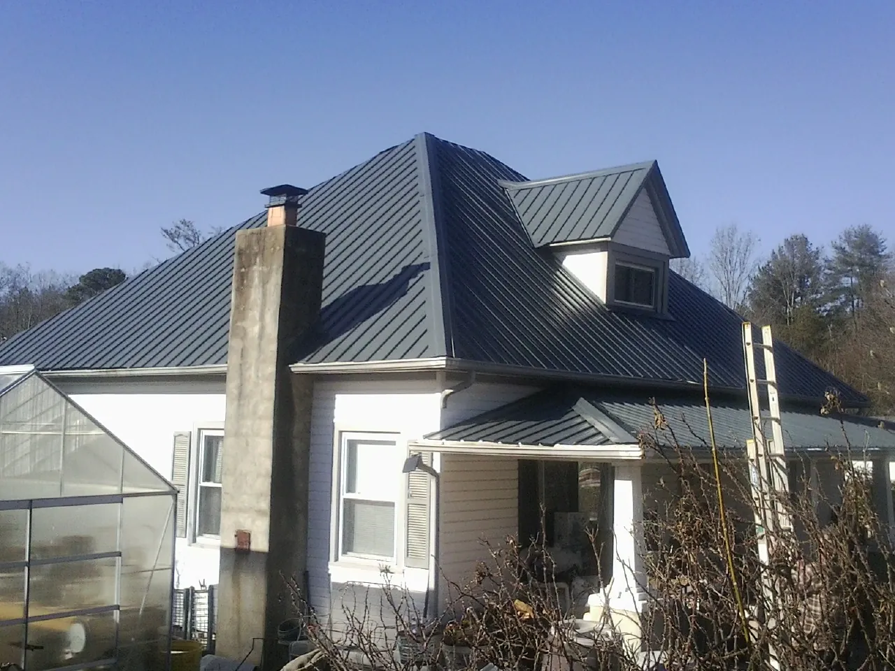 Dark blue standing seam metal roof on a white farmhouse with dormer — Slate & Tile Roof Repair by Roofing Brothers in Swiftwater
