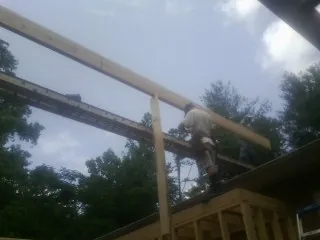 Carpenter setting a ridge beam over a new addition frame — Ice Dam Removal by Roofing Brothers in Swiftwater