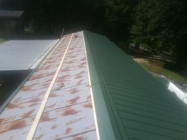 Old rusted panels beside newly installed green metal roofing — Wind Damage Roof Repair by Roofing Brothers in Swiftwater