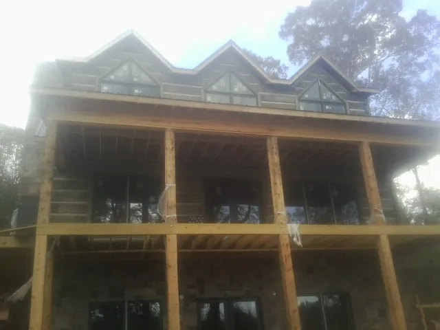 Dormers and porch framing on a large log home under construction — Roof Coating work by our crew in Swiftwater
