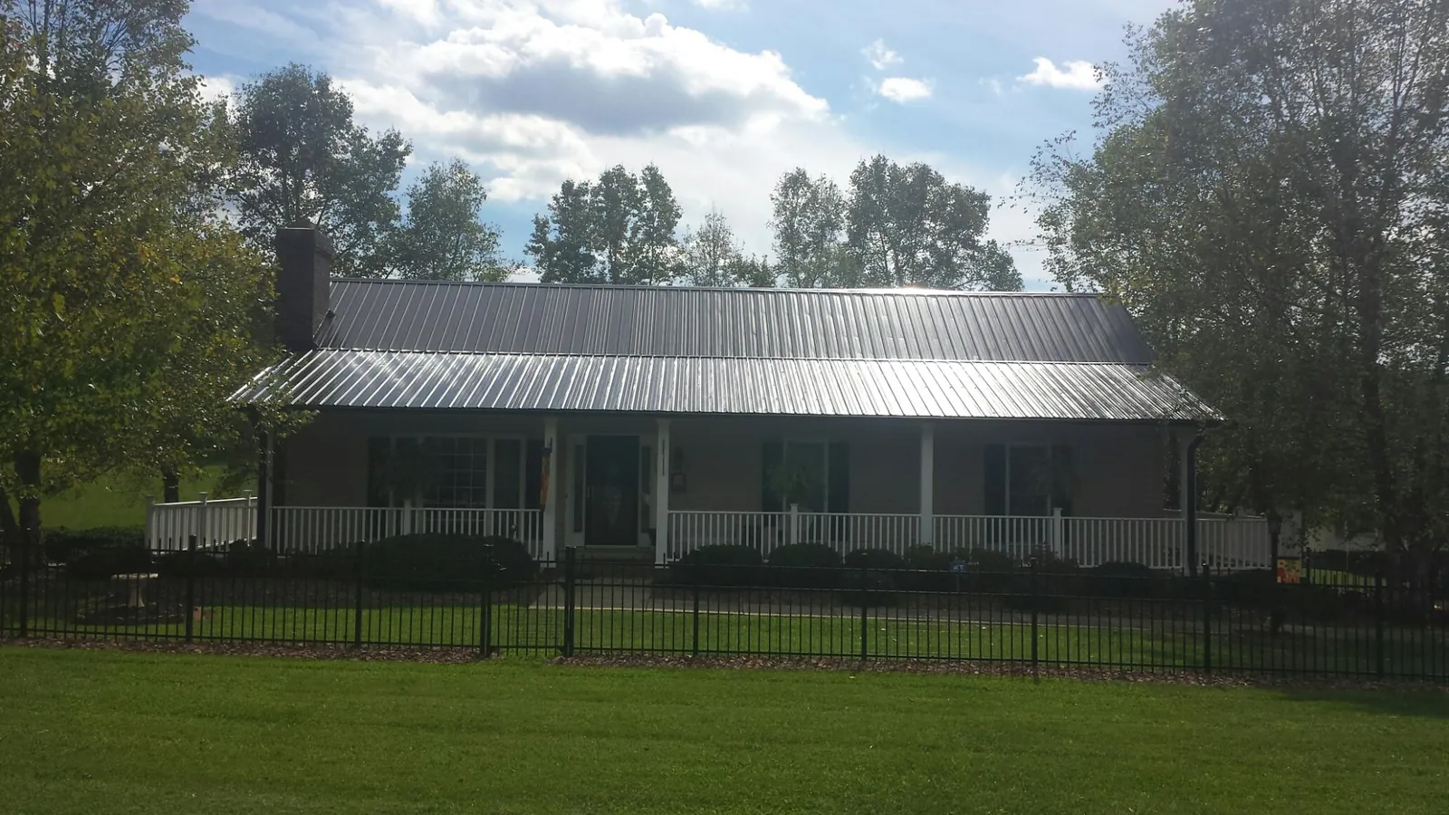 Gray metal roof on a brick ranch with a full width front porch — Gutter Guard Installation work by our crew in Swiftwater