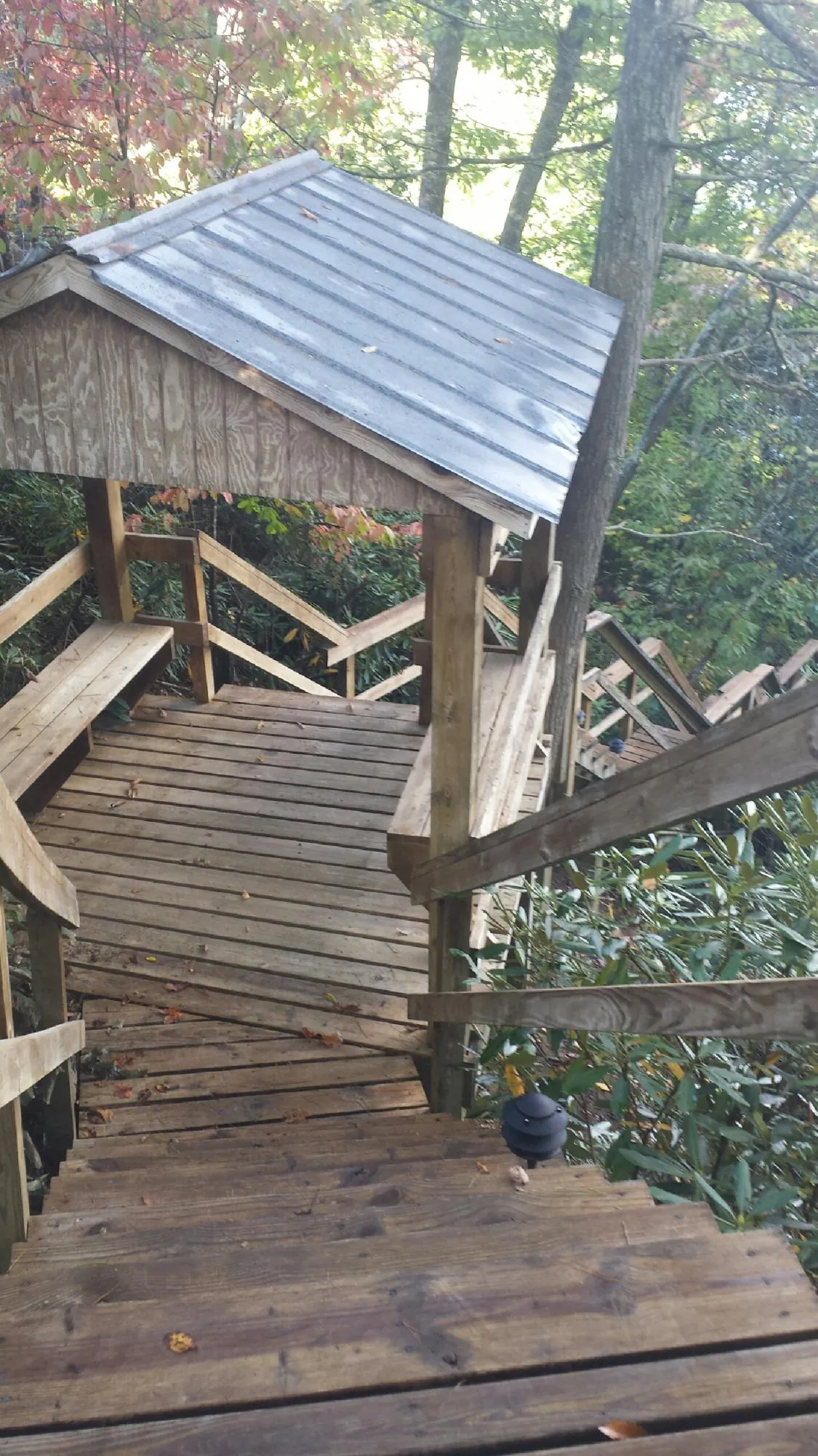 Metal roofed shelter over wooden steps on a wooded walkway — Skylight Repair & Installation work by our crew in Swiftwater
